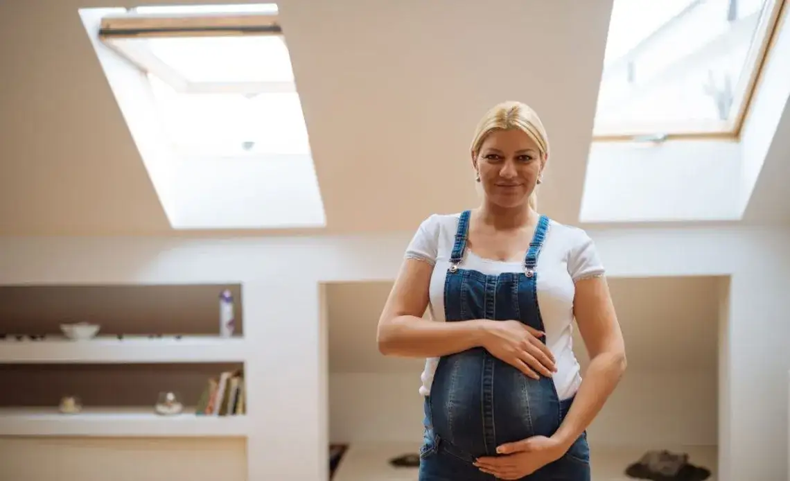 Kobieta w ciąży wietrząca pokój po malowaniu